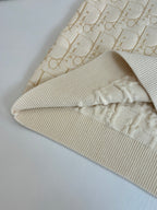 Cream jacquard knit sweater sleeve with ribbed cuff, close-up detail