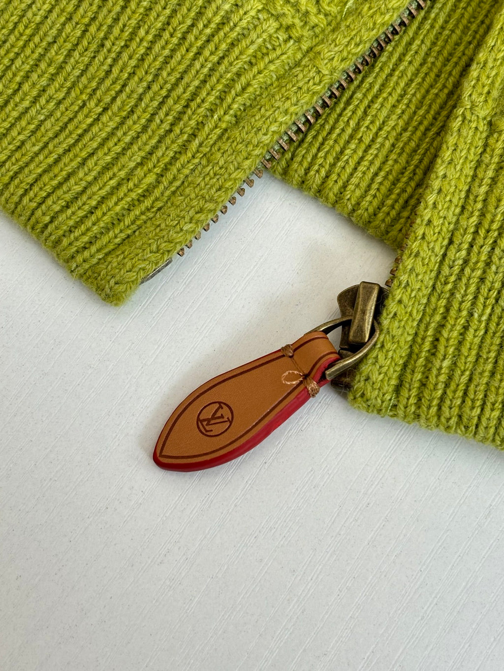 Lime green knit cardigan sleeve with zipper and brown leather pull tab