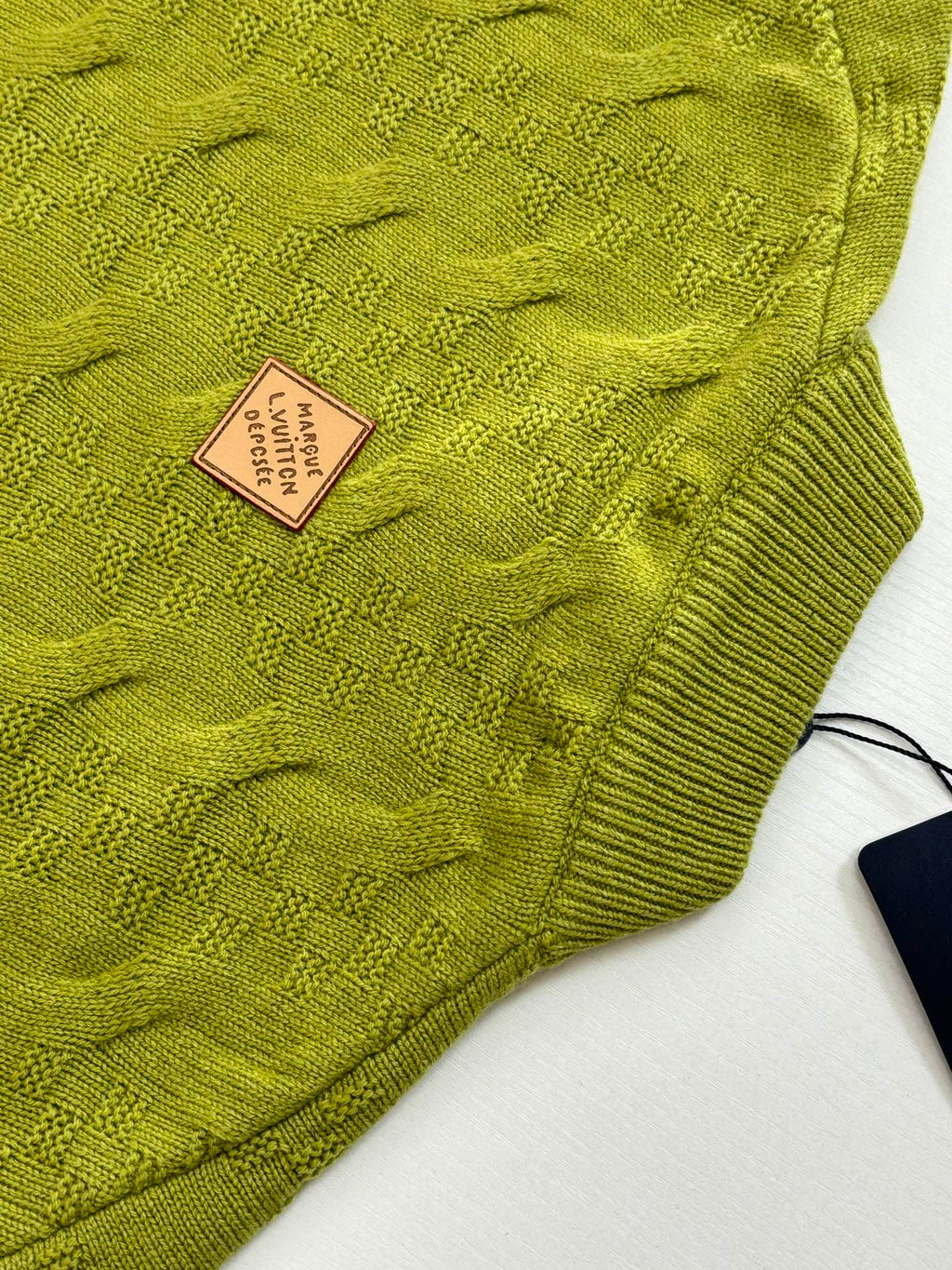 Green knit sweater fabric texture with Louis Vuitton square size label
