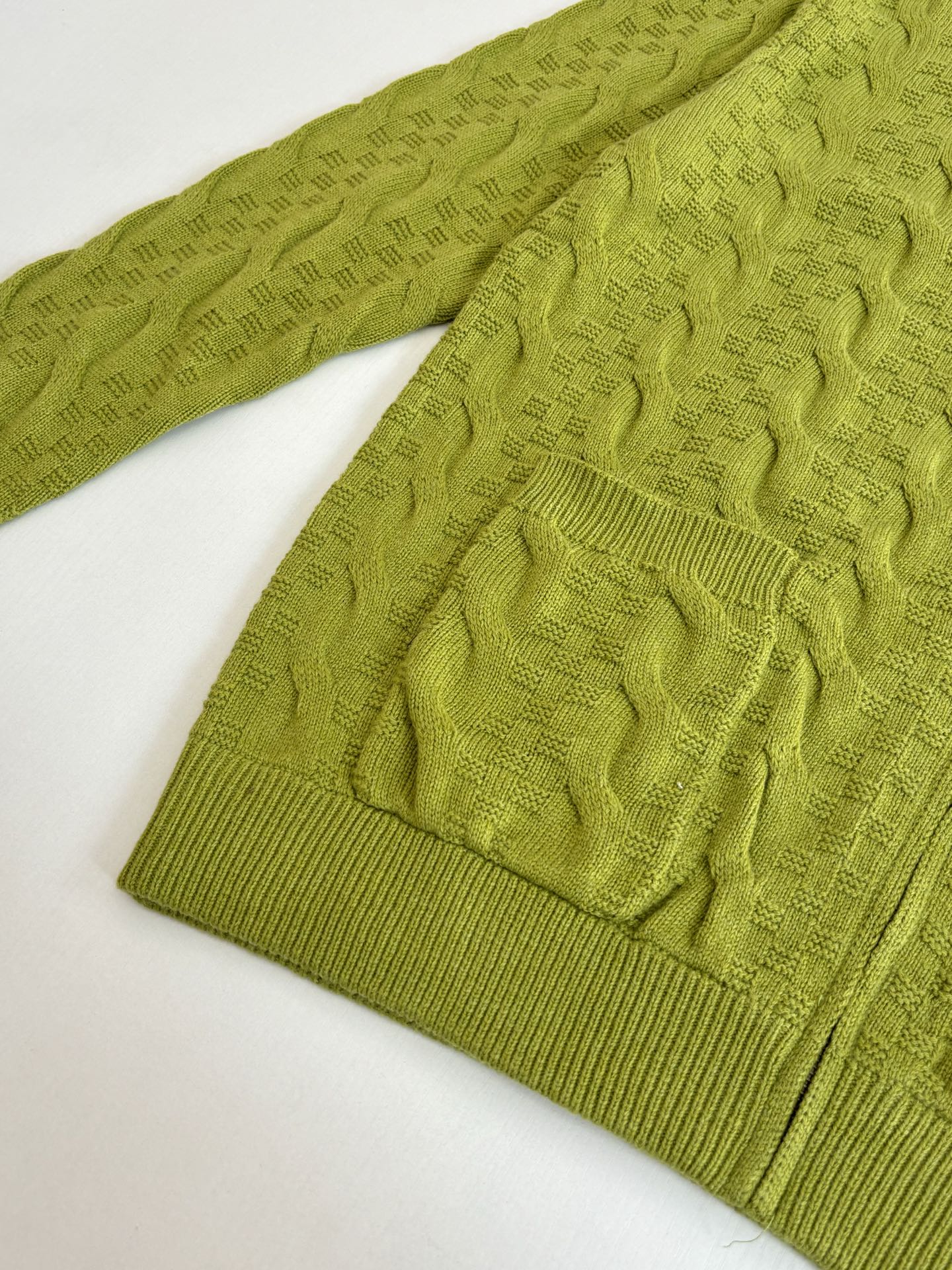 Lime green knit cardigan sleeve and hem with textured stitch pattern