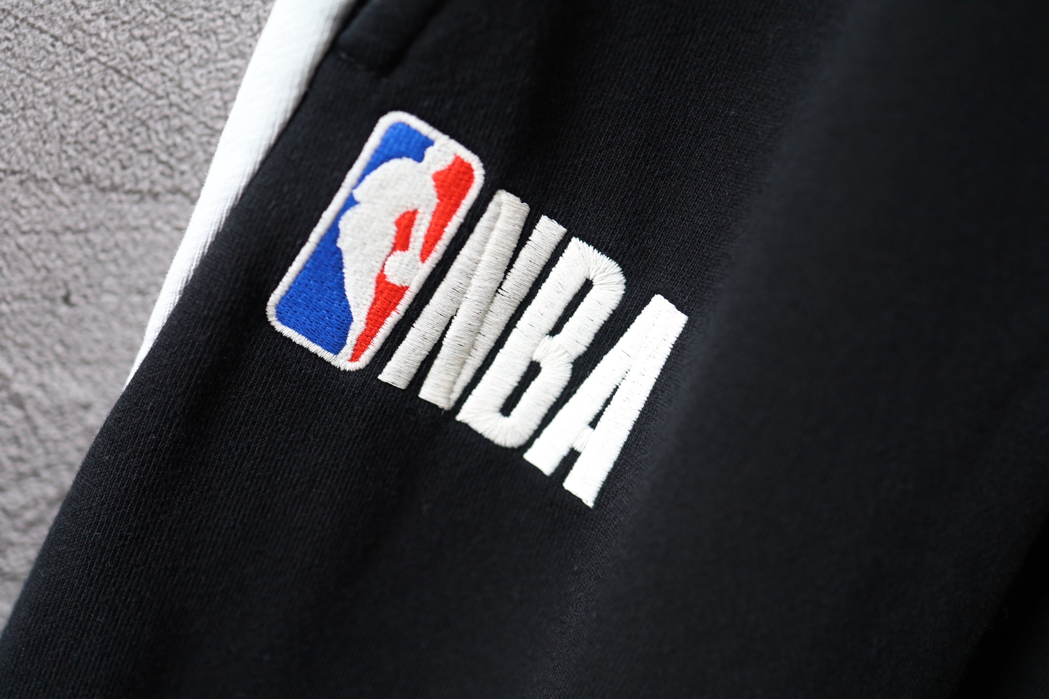 Black Balenciaga pants with colorful “NBA” logo patch