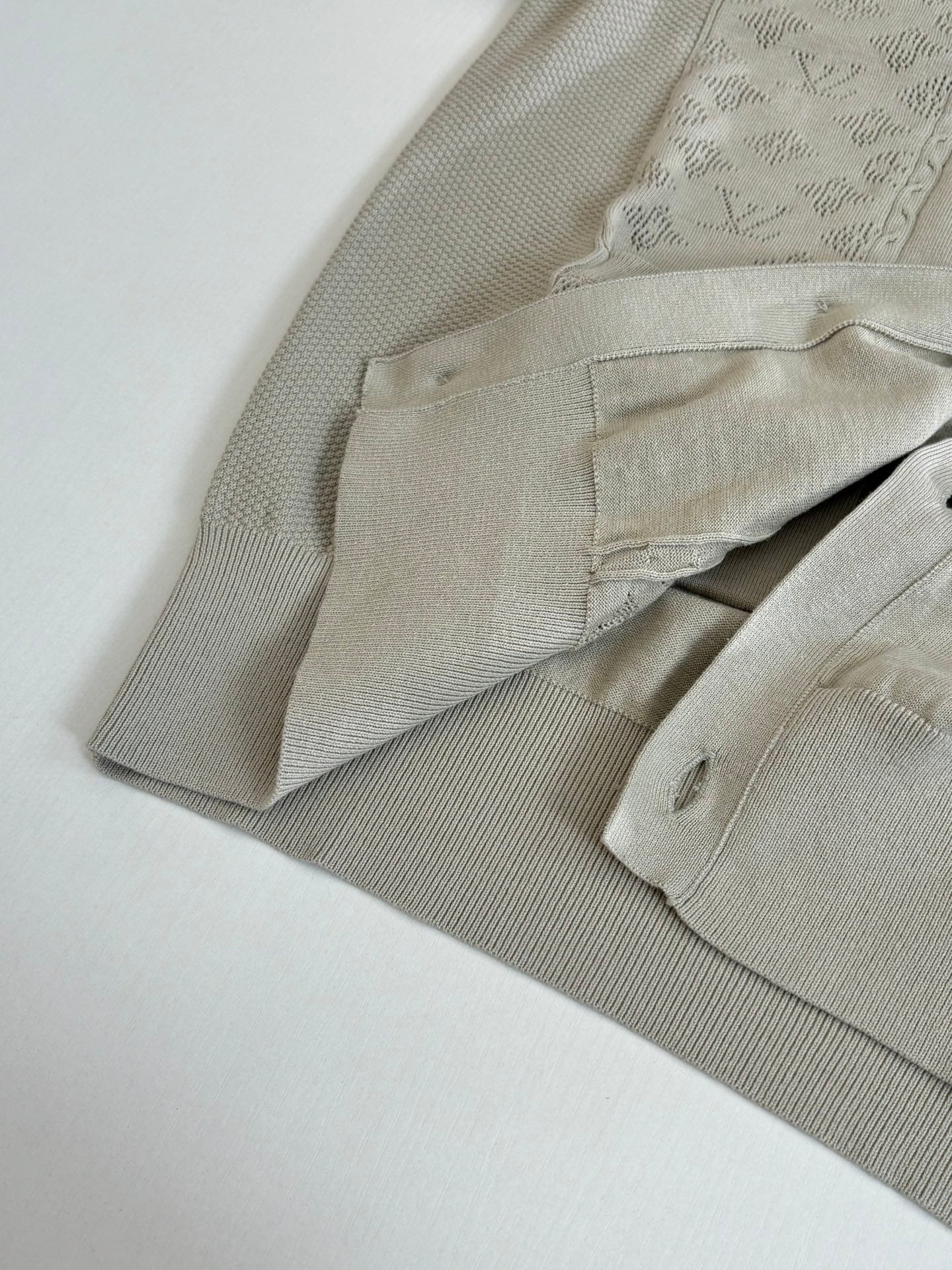 Beige cardigan sleeve and cuff with ribbed texture and angled folded view