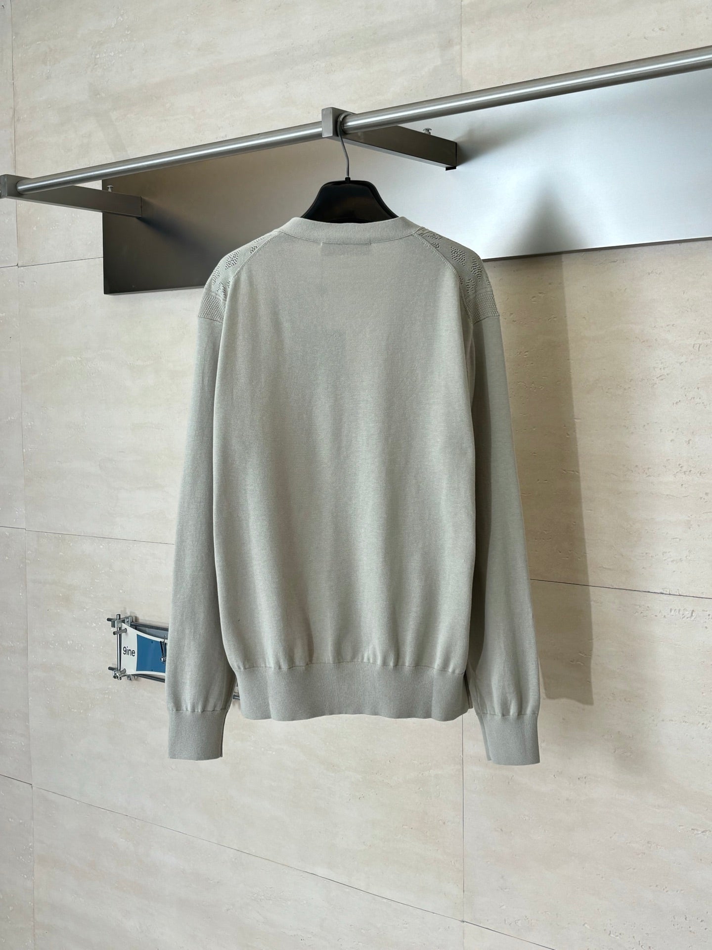 Light cream knit cardigan on hanger, back view with ribbed cuffs and hem