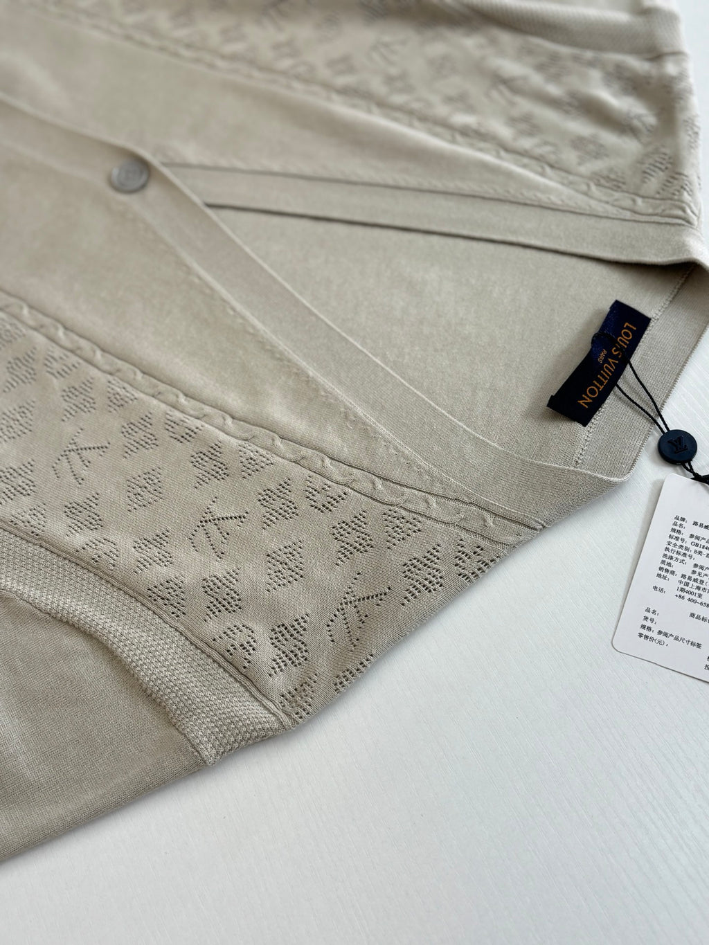 Light cream knit cardigan close-up of button placket and embossed pattern