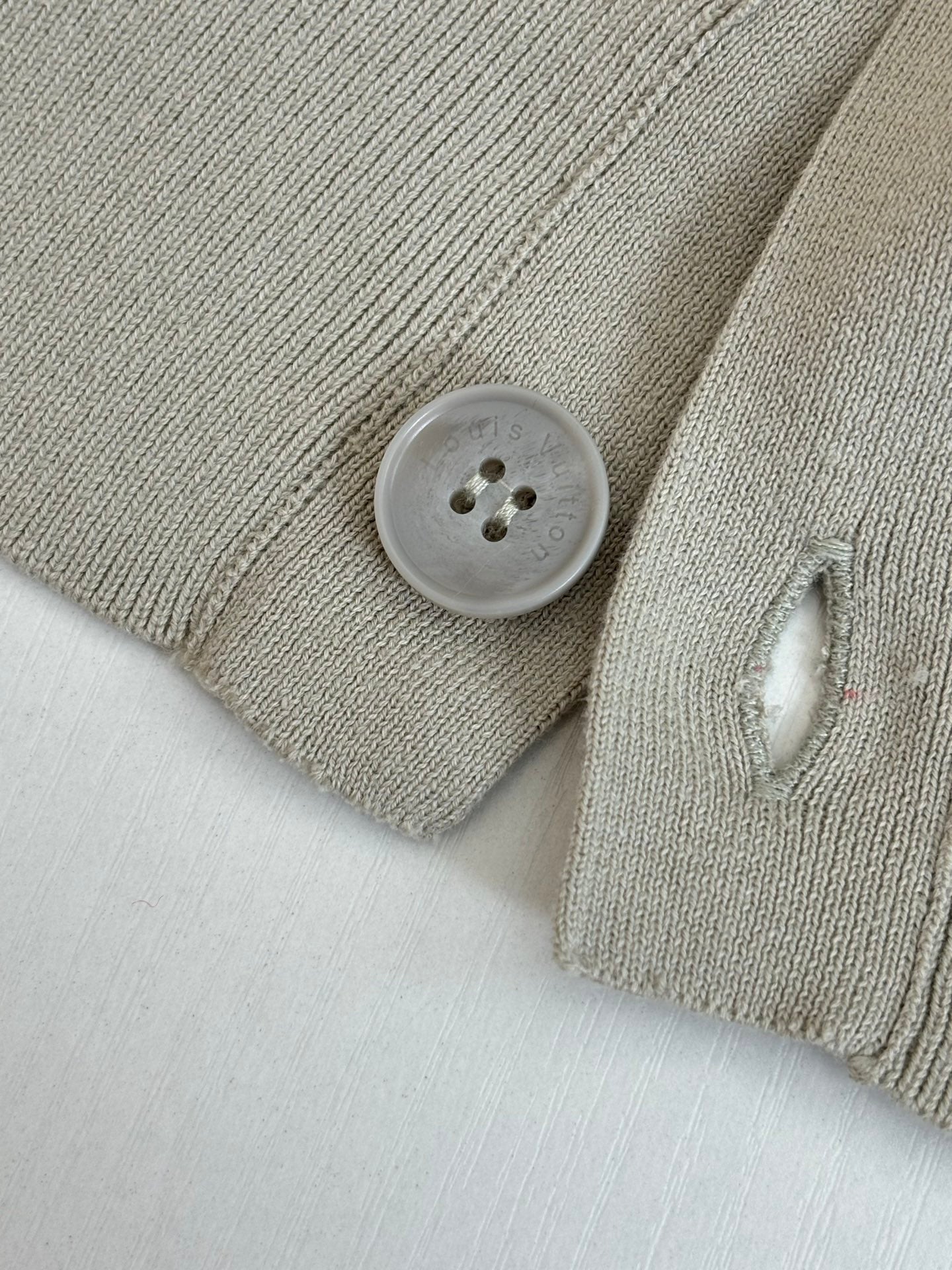 Light cream knit cardigan close-up of round button on ribbed cuff