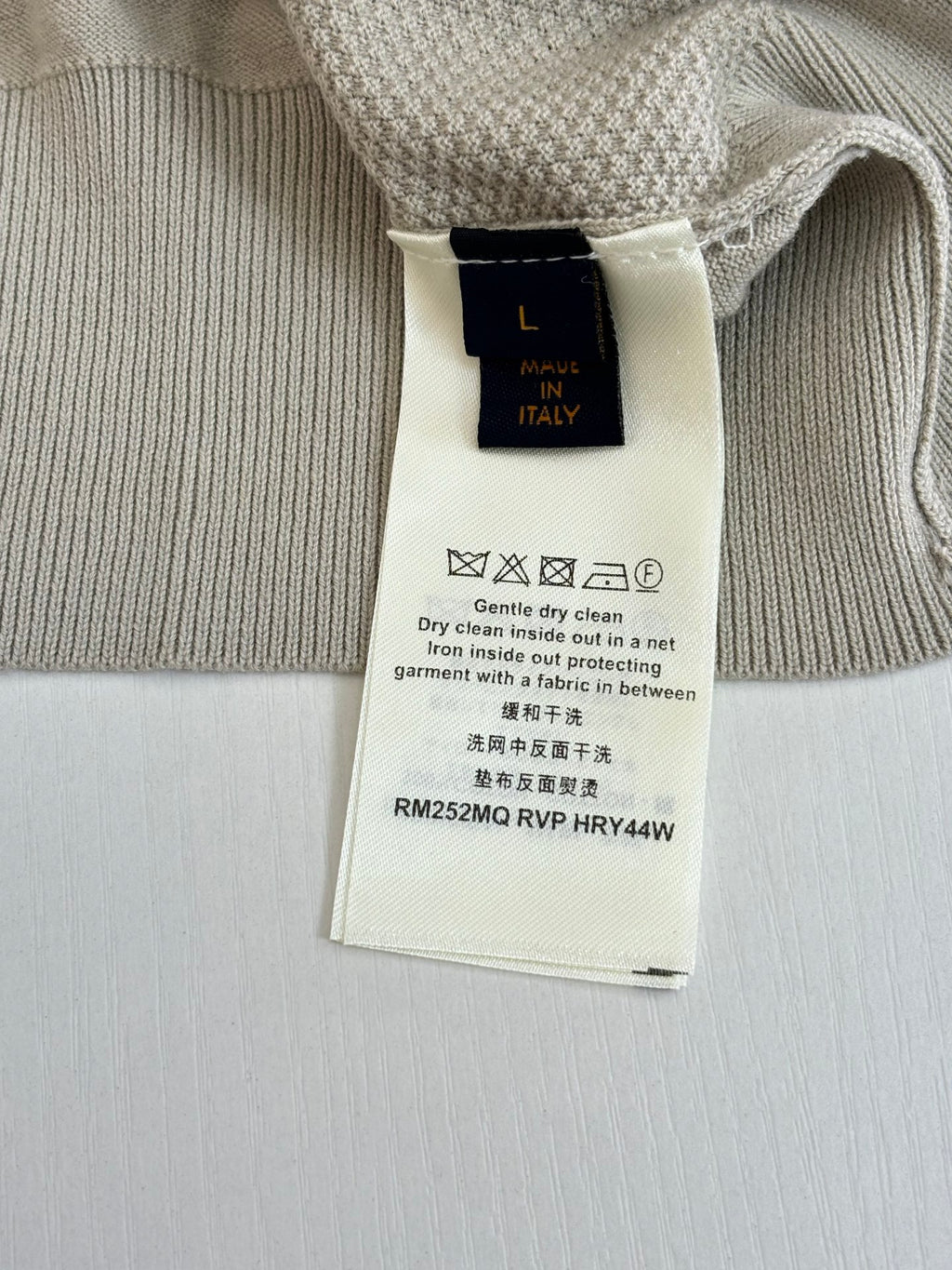 Light cream knit cardigan care tag with size “L” and “Italy”