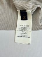 Beige cardigan fabric tag near collar with care instructions visible