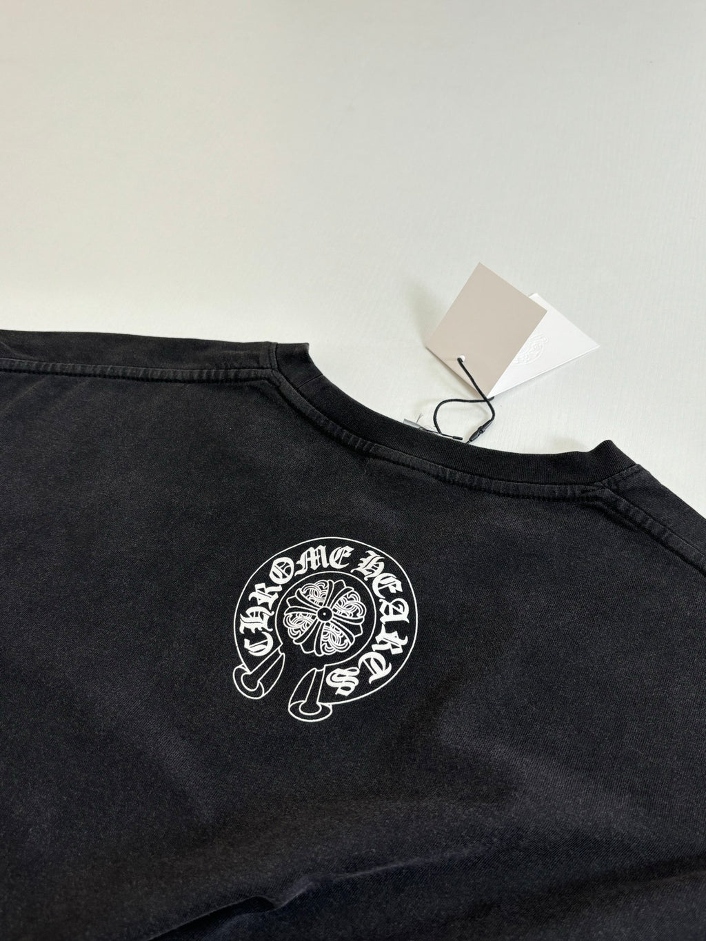 Dark long-sleeve T-shirt with circular crest graphic at the chest and neck tag