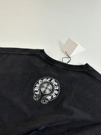 Dark long-sleeve T-shirt with circular crest graphic at the chest and neck tag