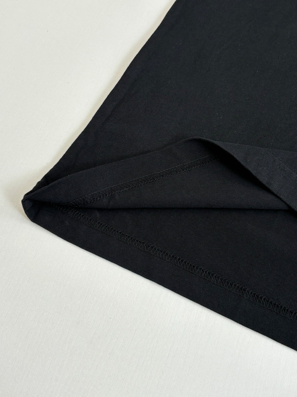 Black short-sleeve T-shirt close-up of curved hem and side seam