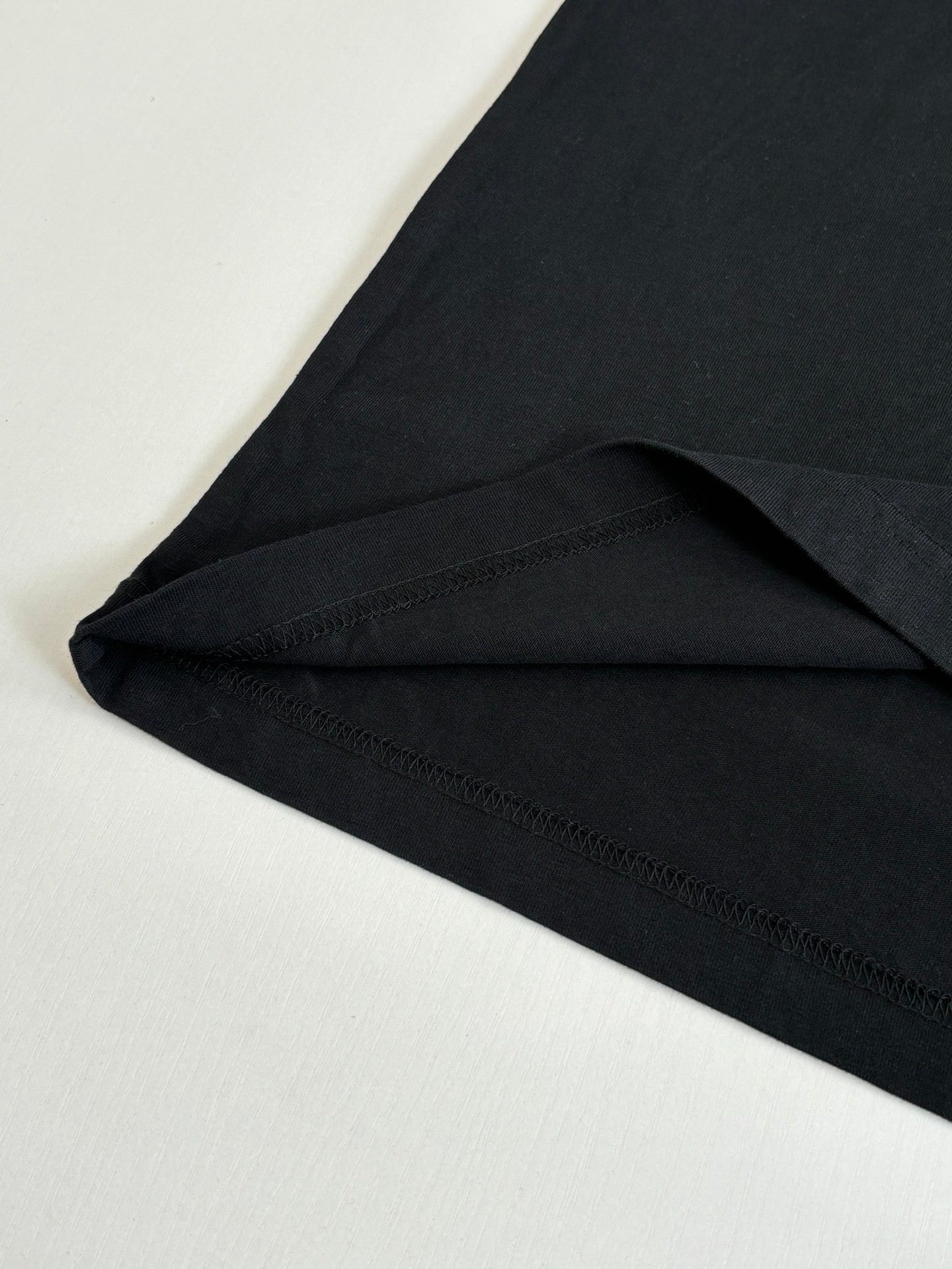Black short-sleeve T-shirt close-up of curved hem and side seam