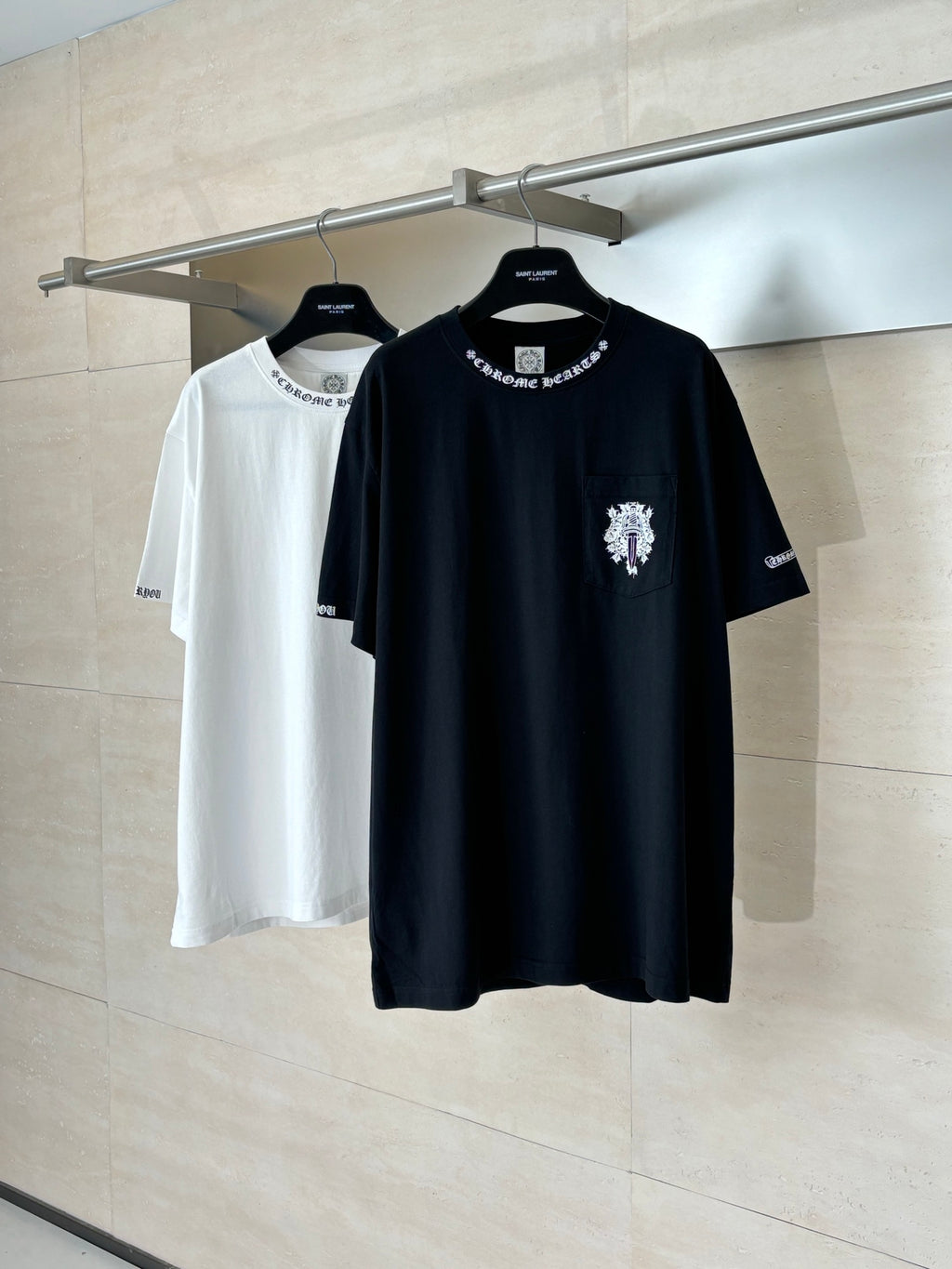 Black and white short-sleeve T-shirts on hangers, each with chest graphic