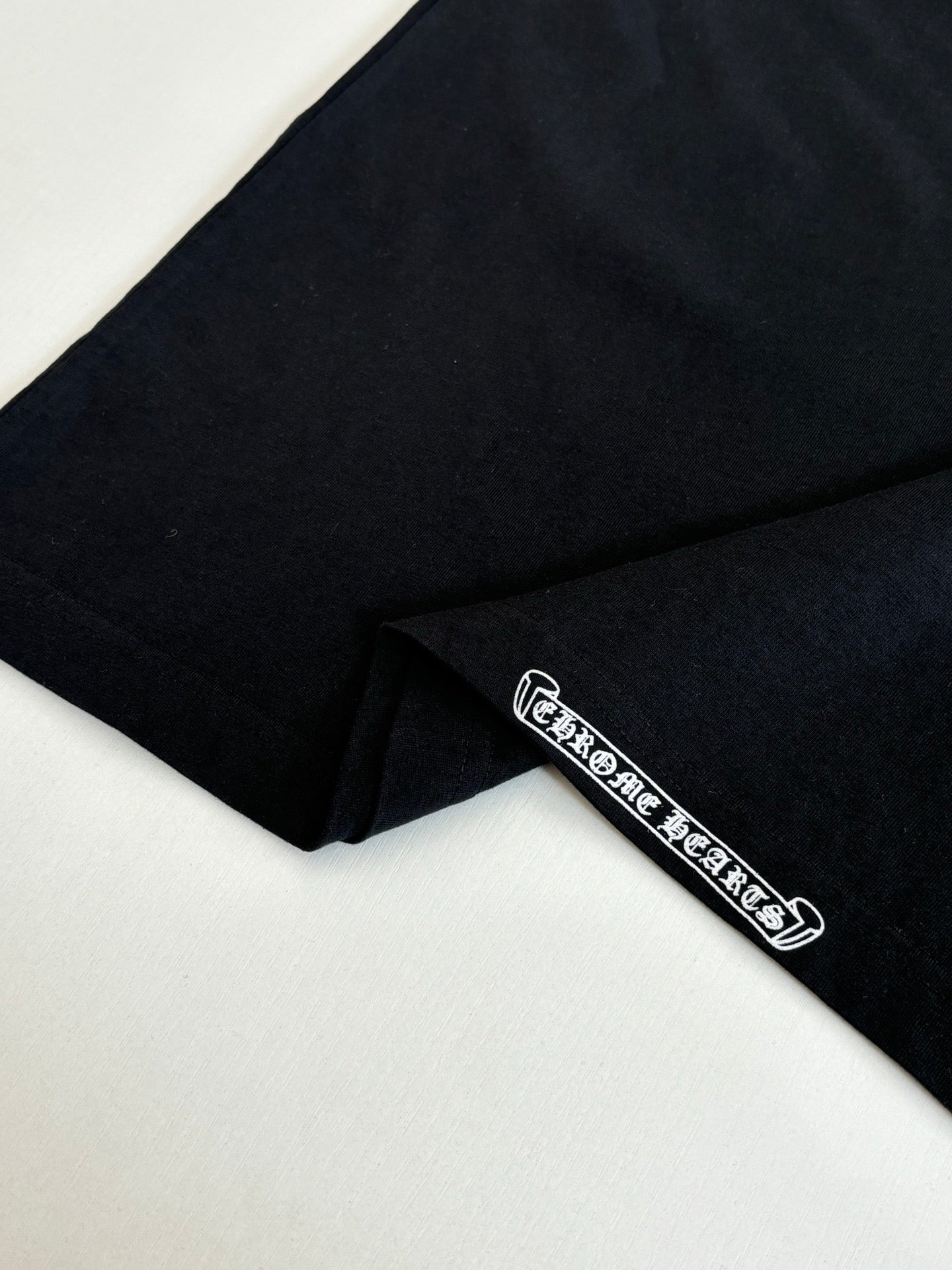 Black T-shirt close-up of sleeve hem with small logo patch