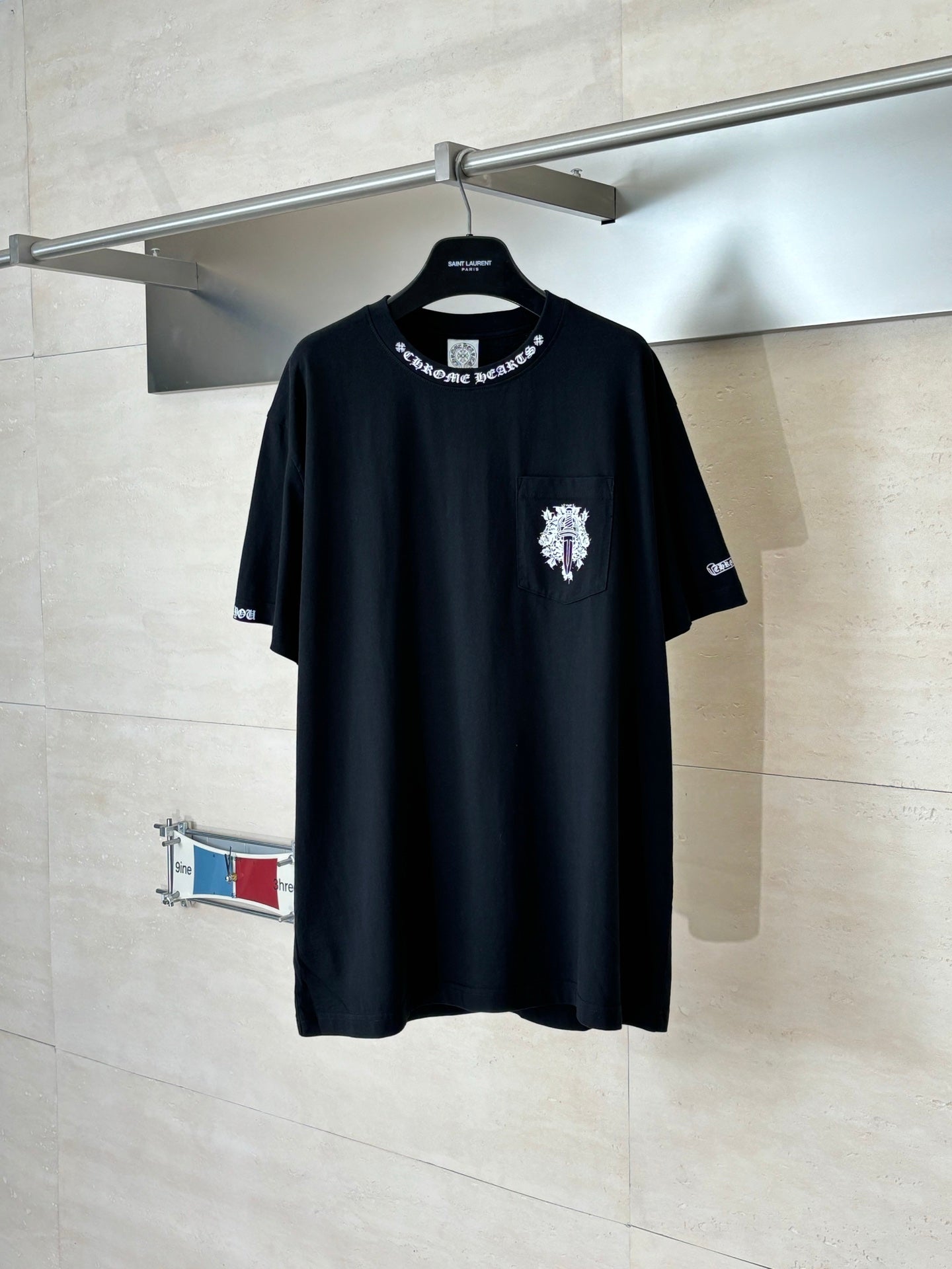 Black crew-neck T-shirt with small chest crest graphic and short sleeves