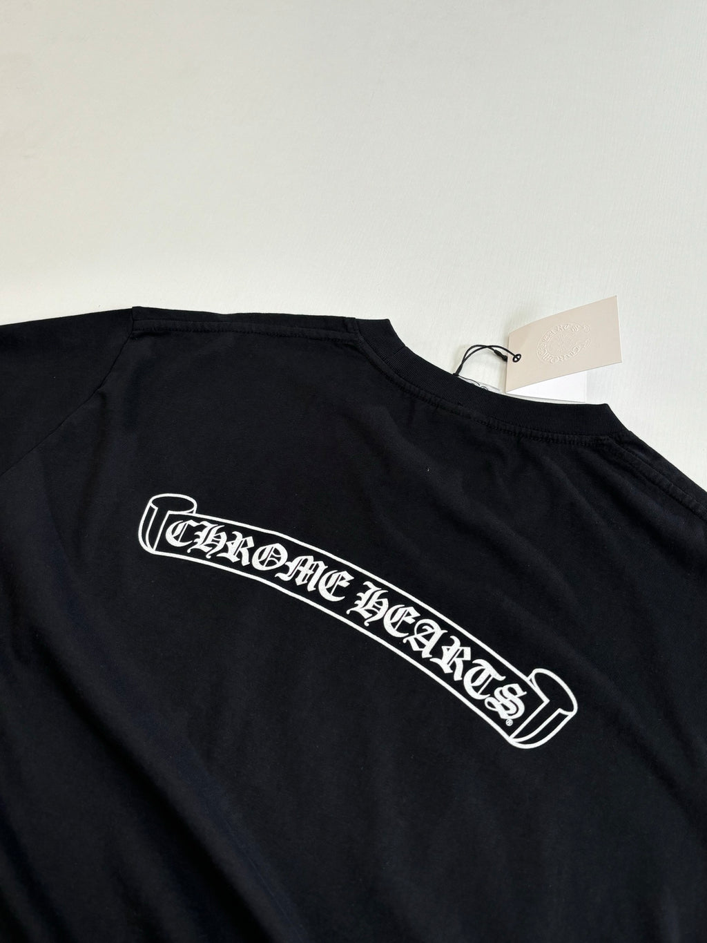 Black short-sleeve T-shirt with long white logo graphic across chest
