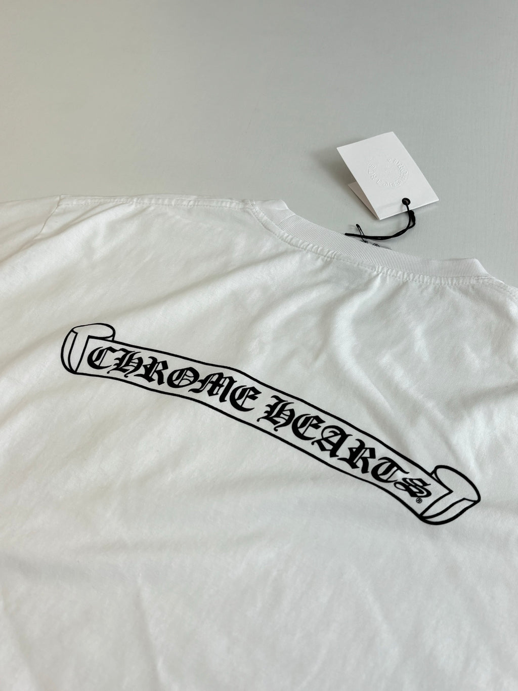 White short-sleeve T-shirt with long black logo graphic across the chest