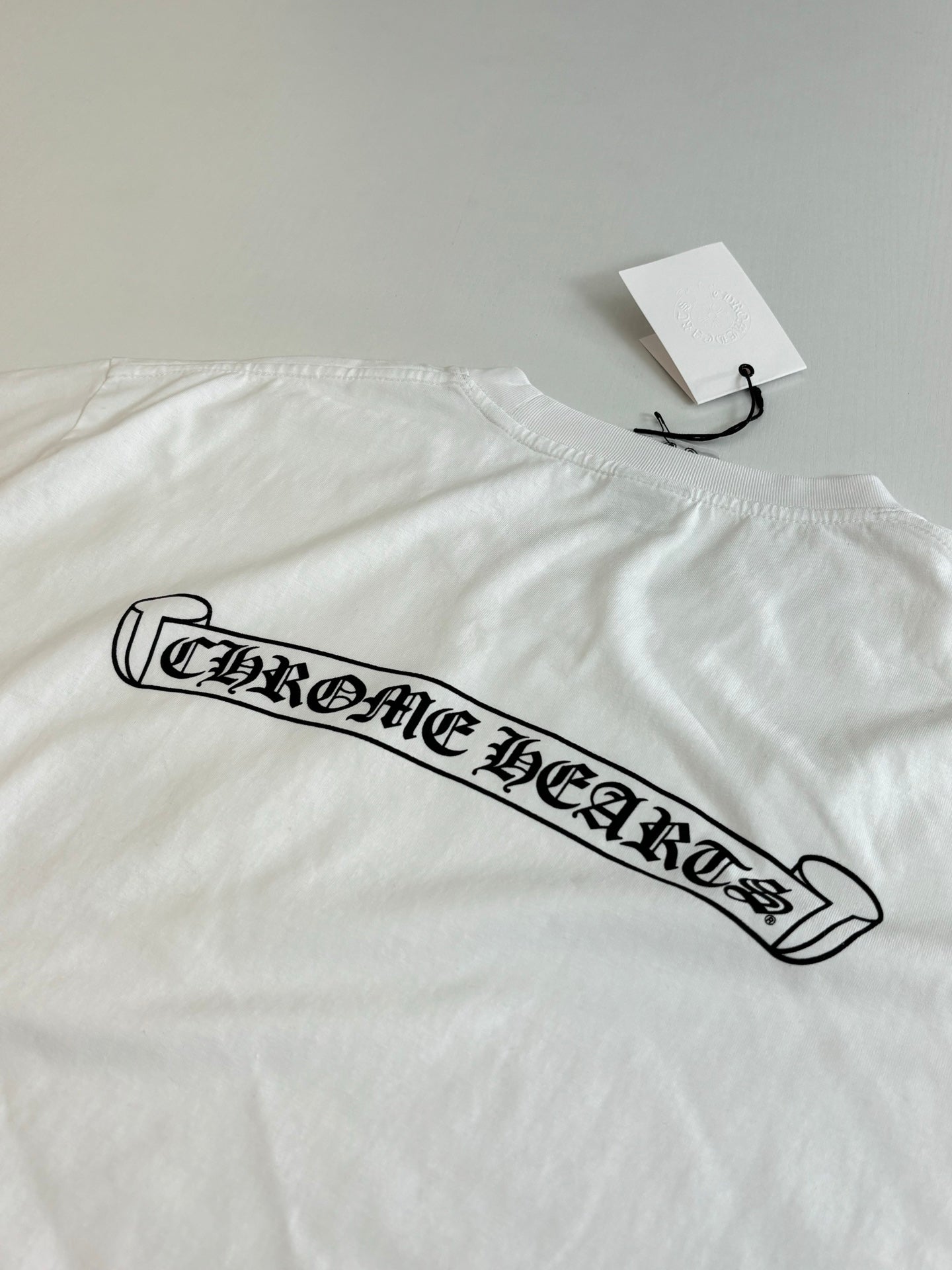 White short-sleeve T-shirt with long black logo graphic across the chest