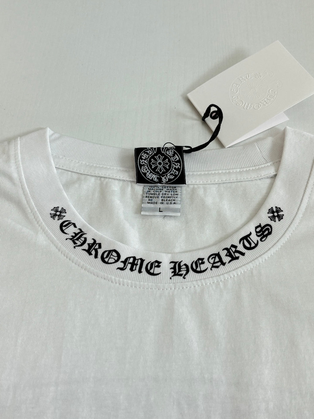 White crew-neck T-shirt with black logo band across the collar