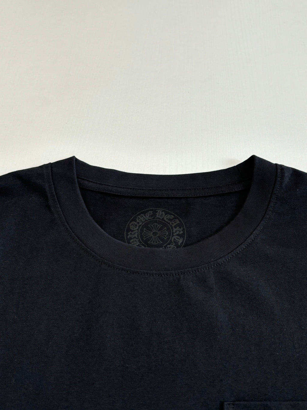 Black crewneck T-shirt with embossed circular neckline logo