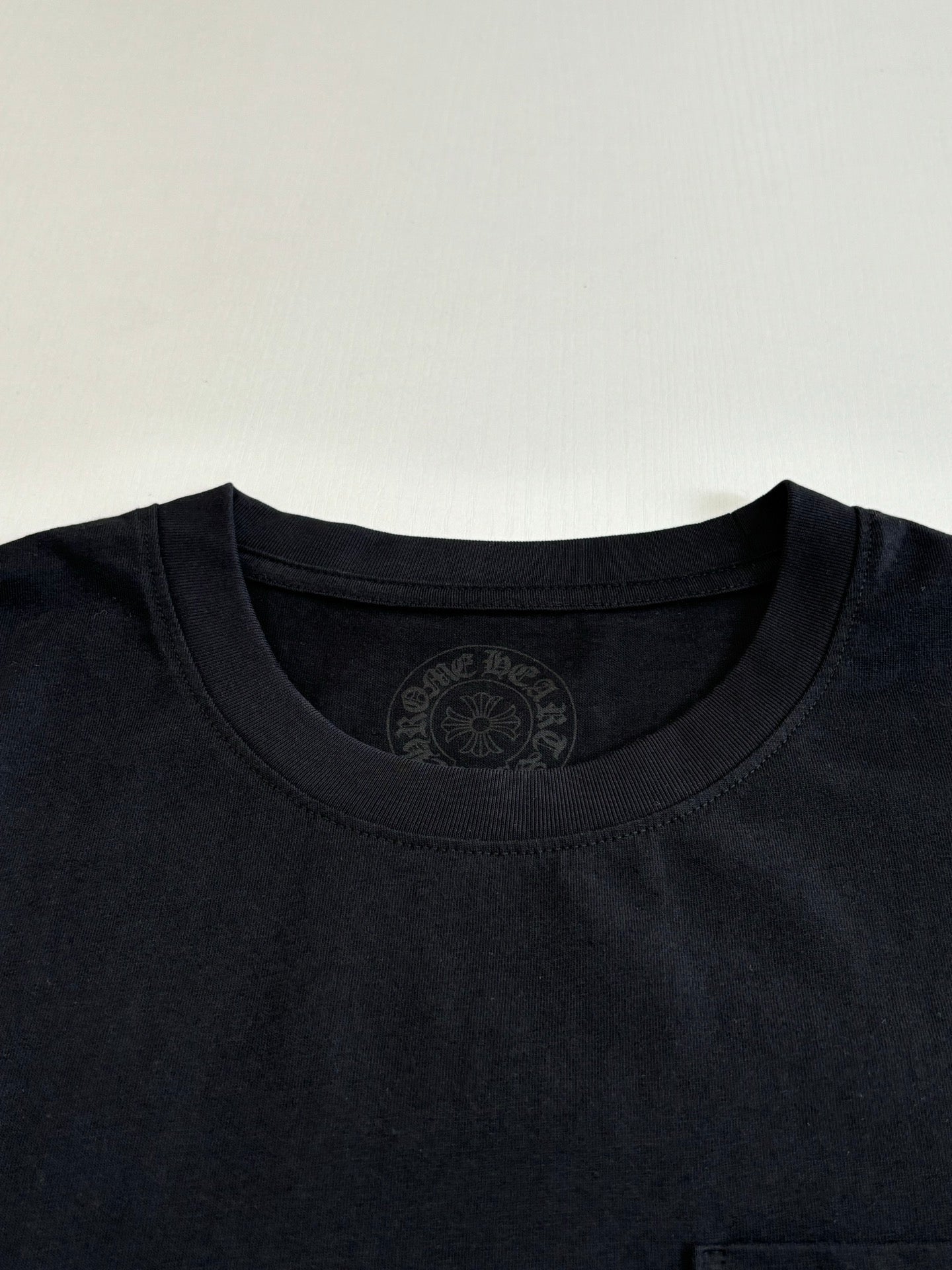 Black crewneck T-shirt with embossed circular neckline logo