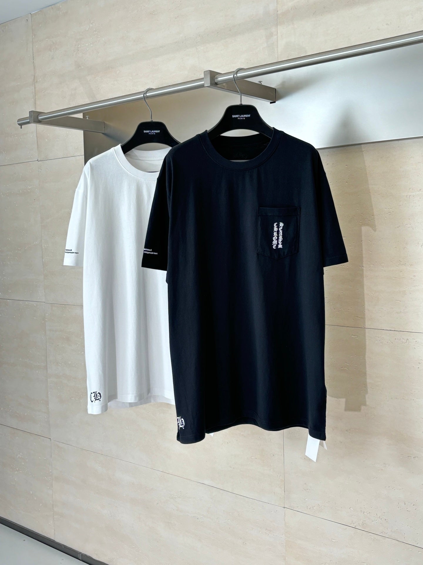 Black and white short-sleeve T-shirts on hangers, each with small chest print