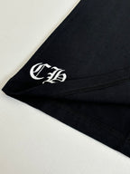 Black T-shirt sleeve with white monogram emblem near hem