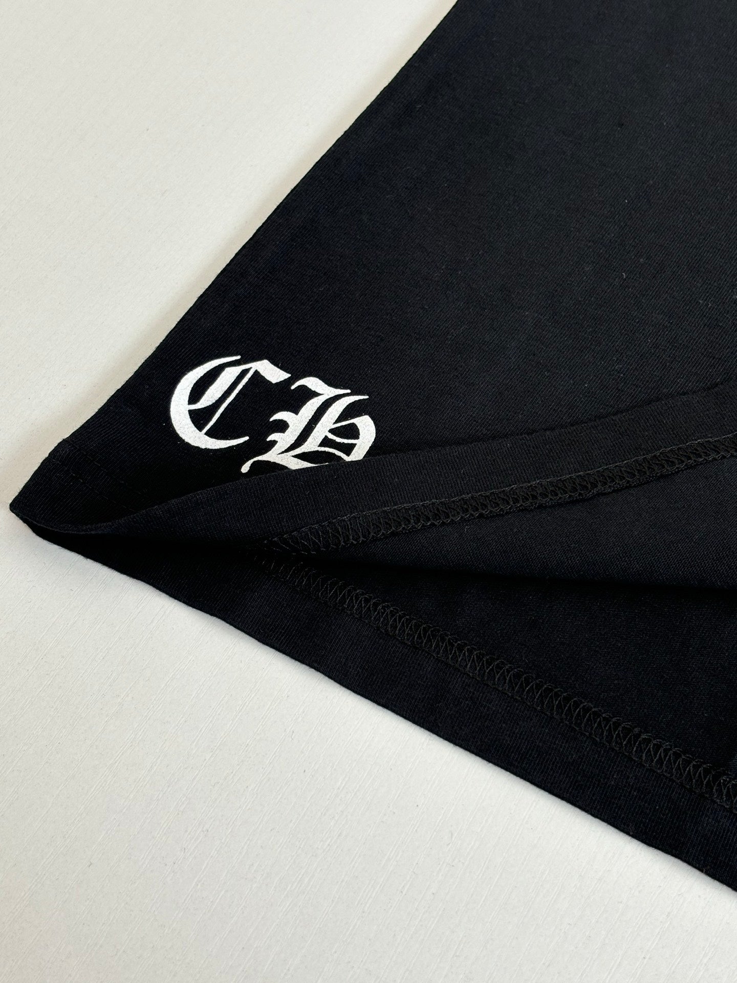 Black T-shirt sleeve with white monogram emblem near hem