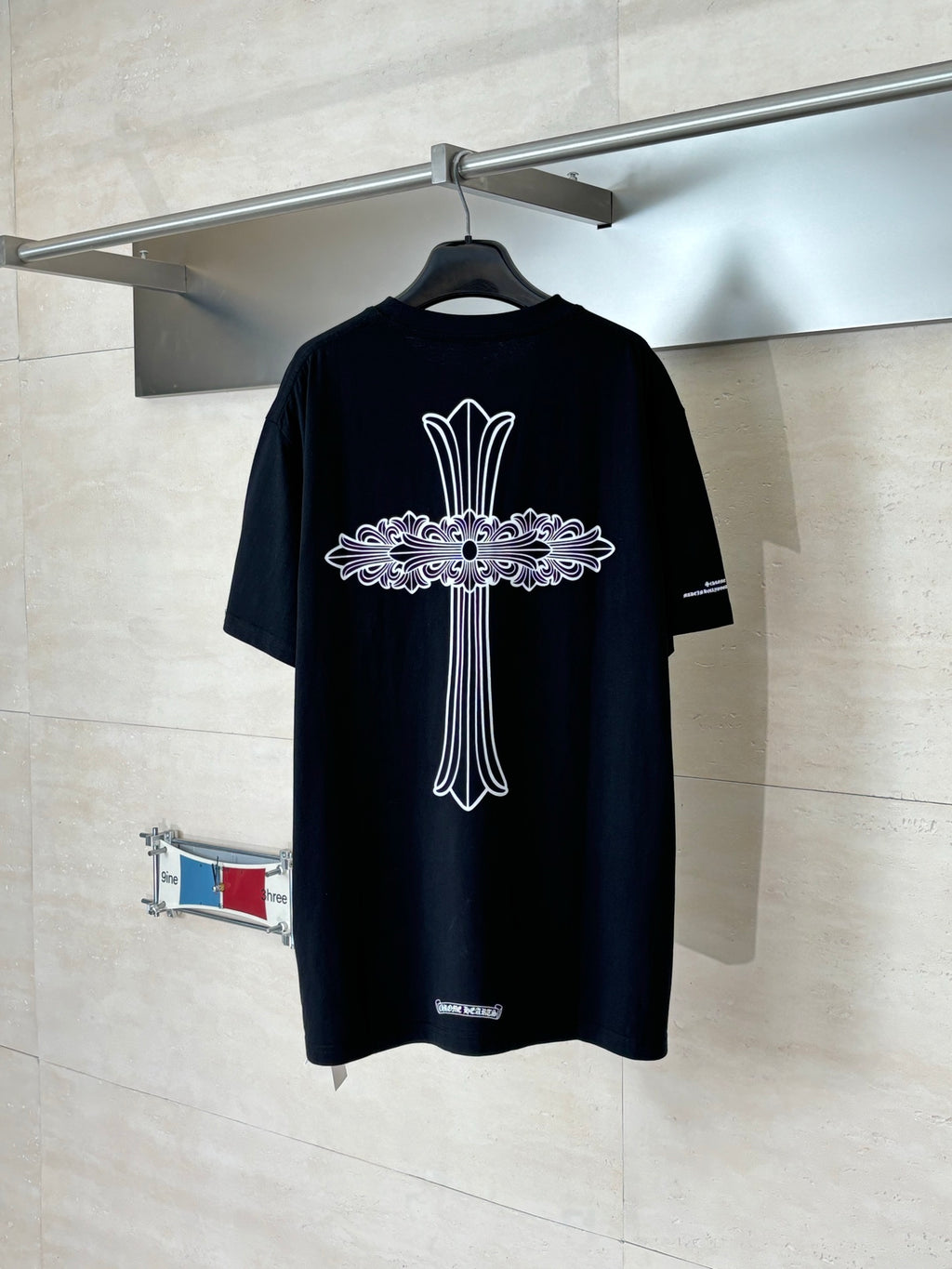 Black crewneck T-shirt on hanger with large back cross-style graphic