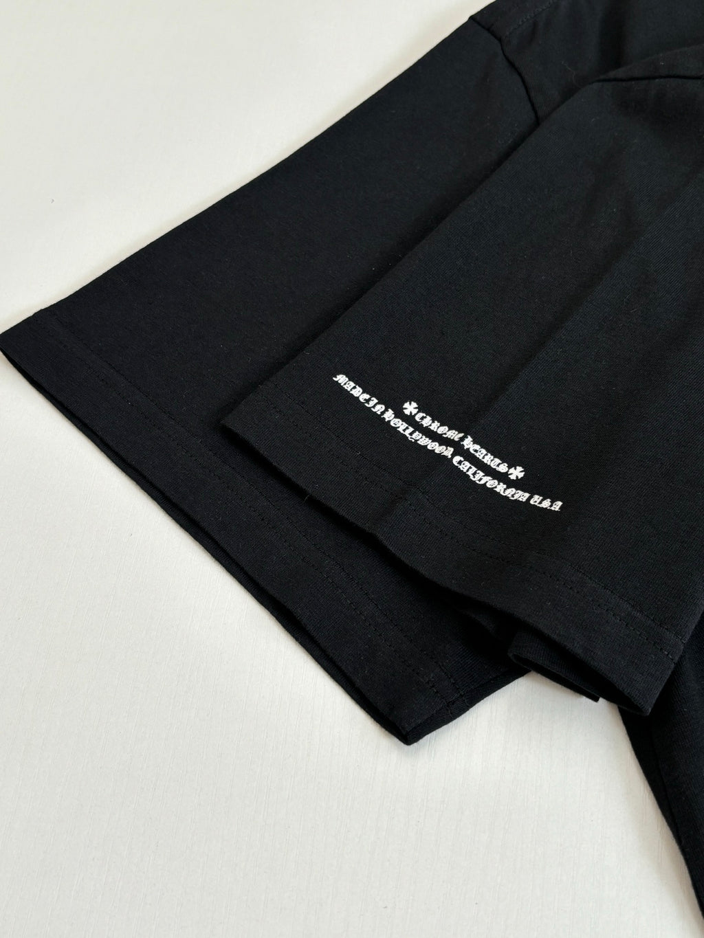 Black T-shirt sleeve with small white text graphic print