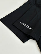 Black T-shirt sleeve with small white logo text near hem