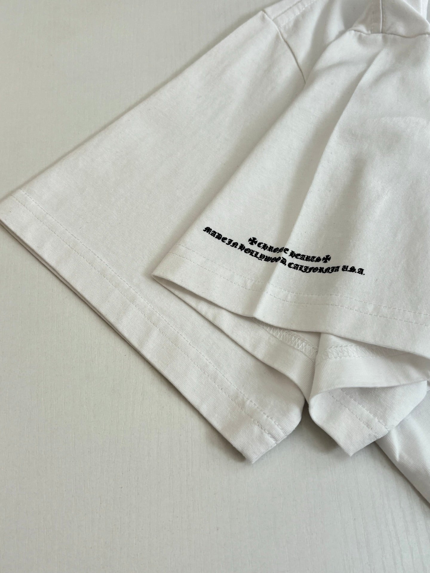 White short-sleeve T-shirt close-up of side seam and small bottom front text print