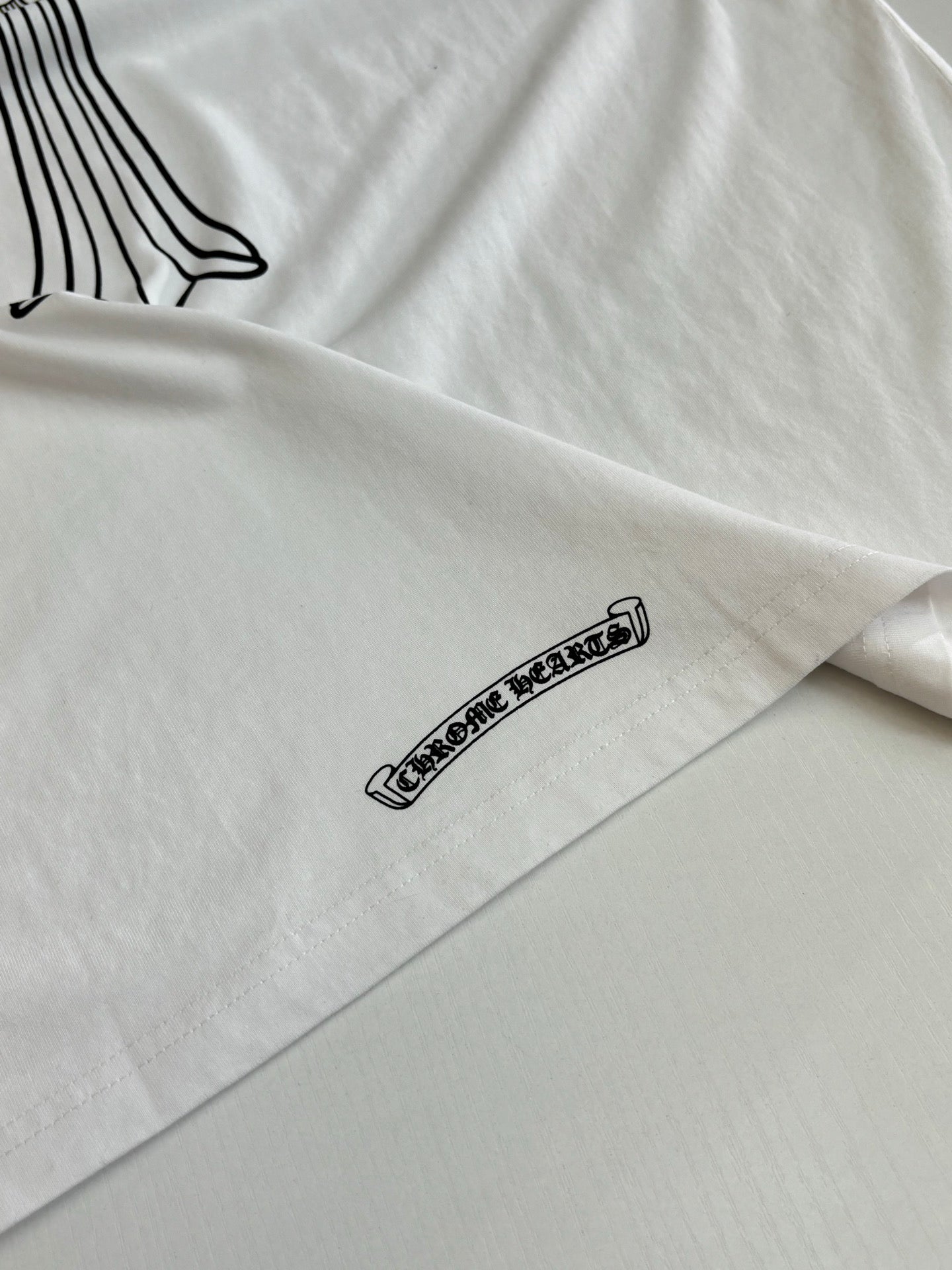 White T-shirt sleeve with small black text logo graphic.