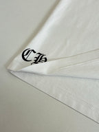 White T-shirt hem corner with small black logo print.