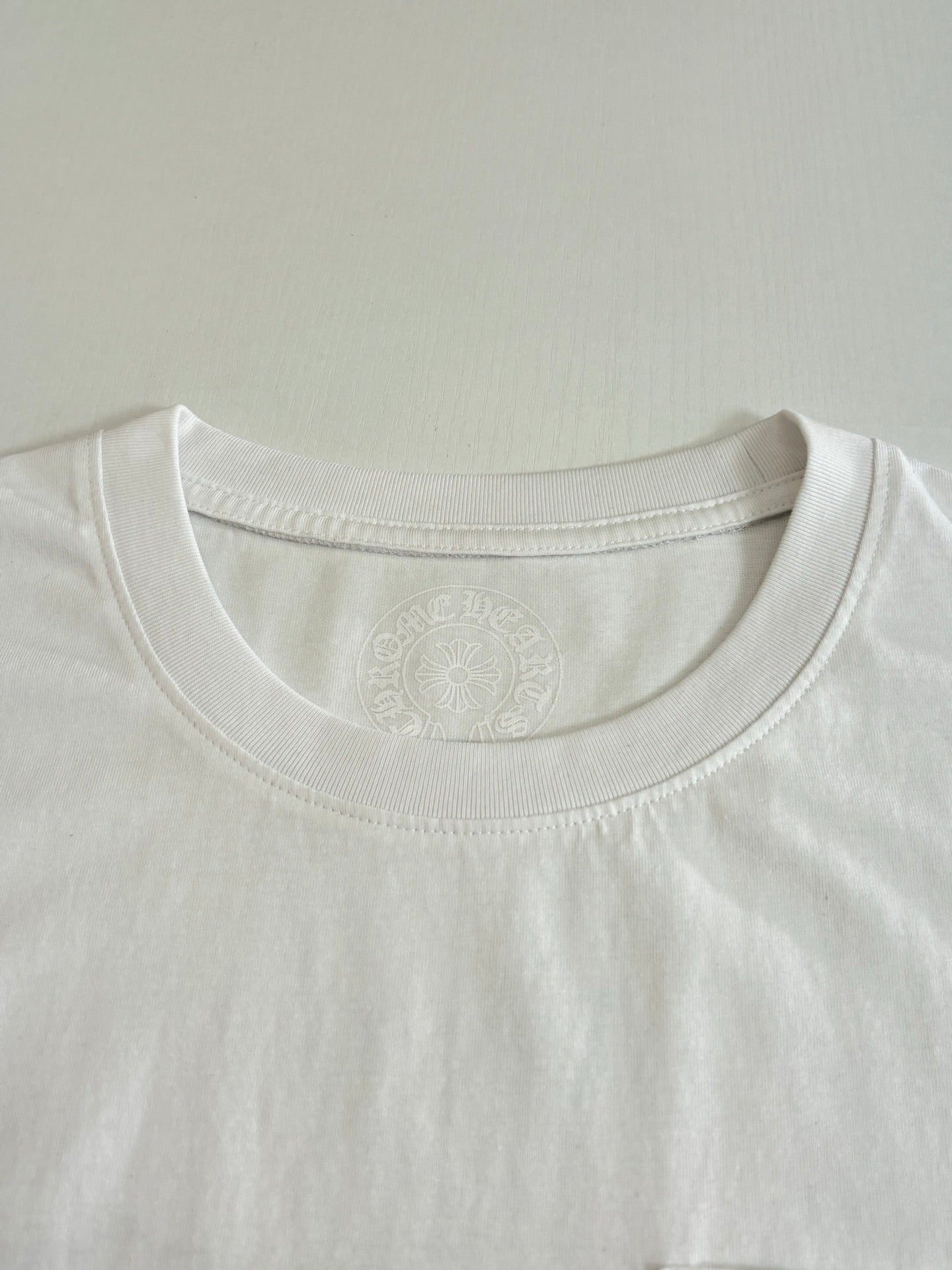 White short-sleeve T-shirt close-up of crew neckline seam and embossed chest mark