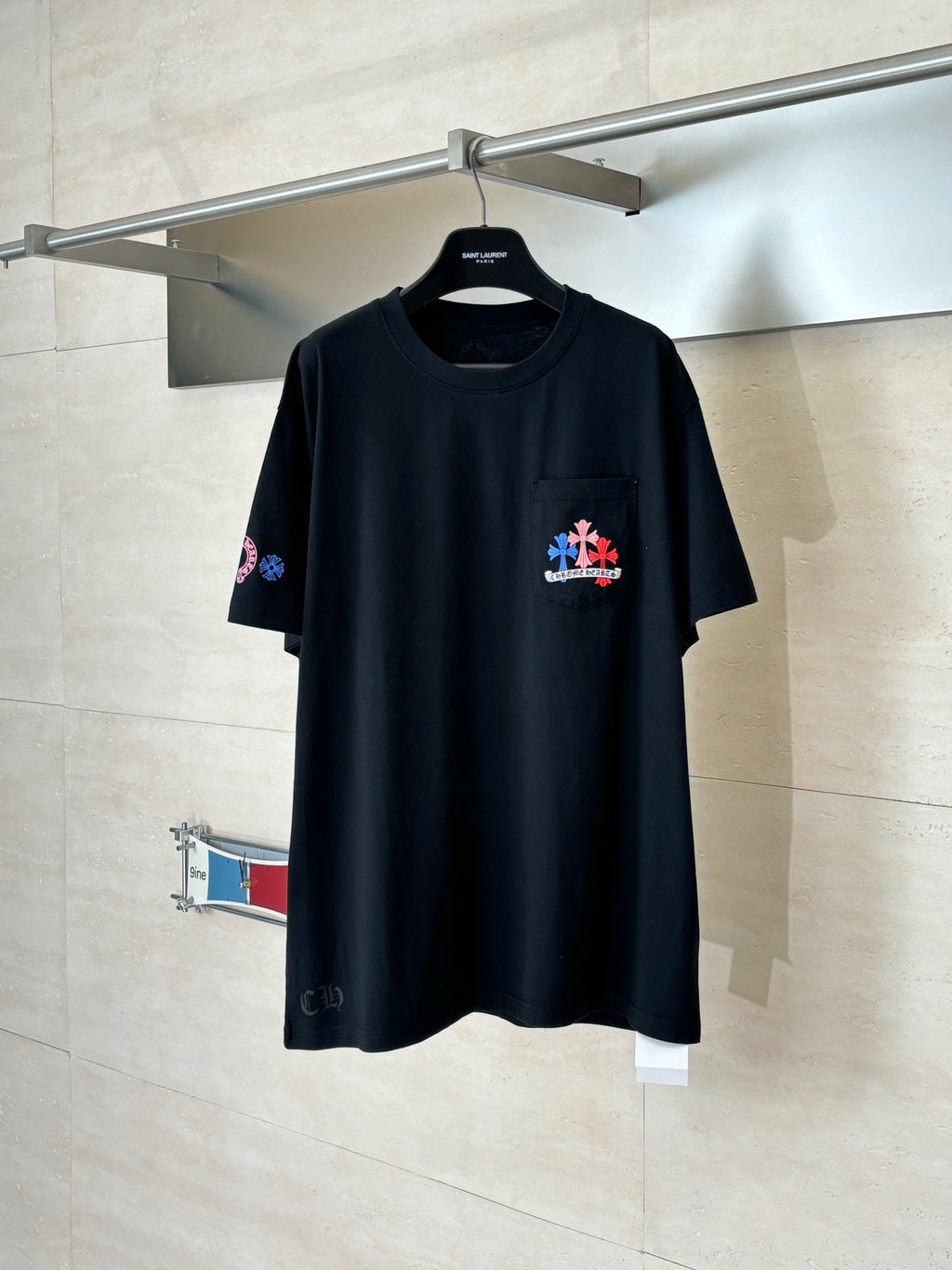 Black crew-neck T-shirt with small multicolor flower logo on left chest