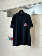 Black crew-neck T-shirt with small multicolor flower logo on left chest