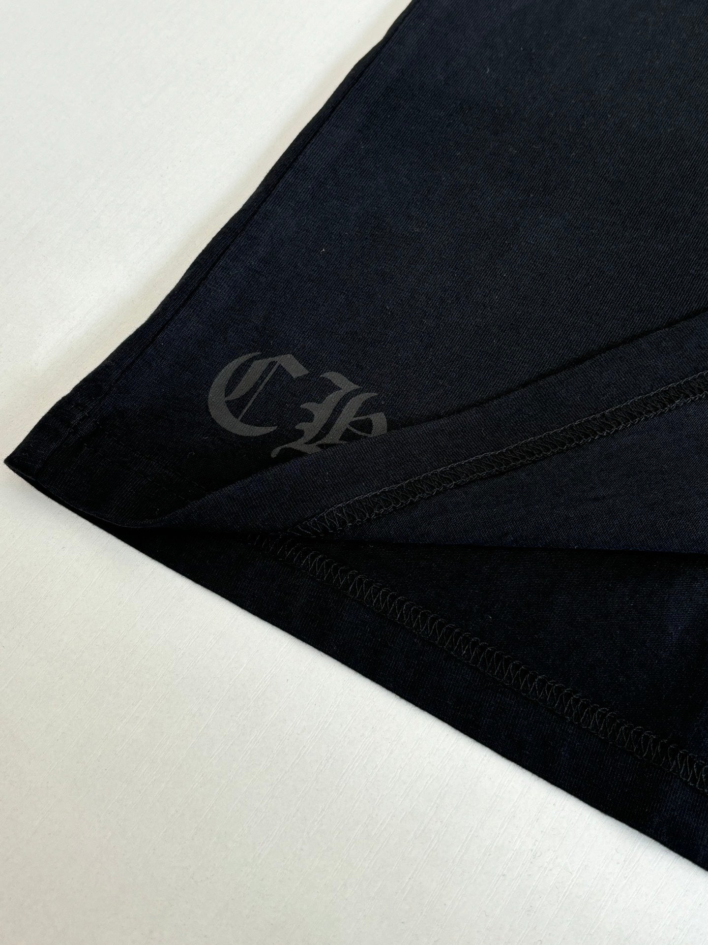 Black short-sleeve T-shirt side hem with subtle gray emblem print