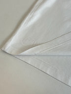 White T-shirt with embossed circular logo on lower sleeve or hem area.