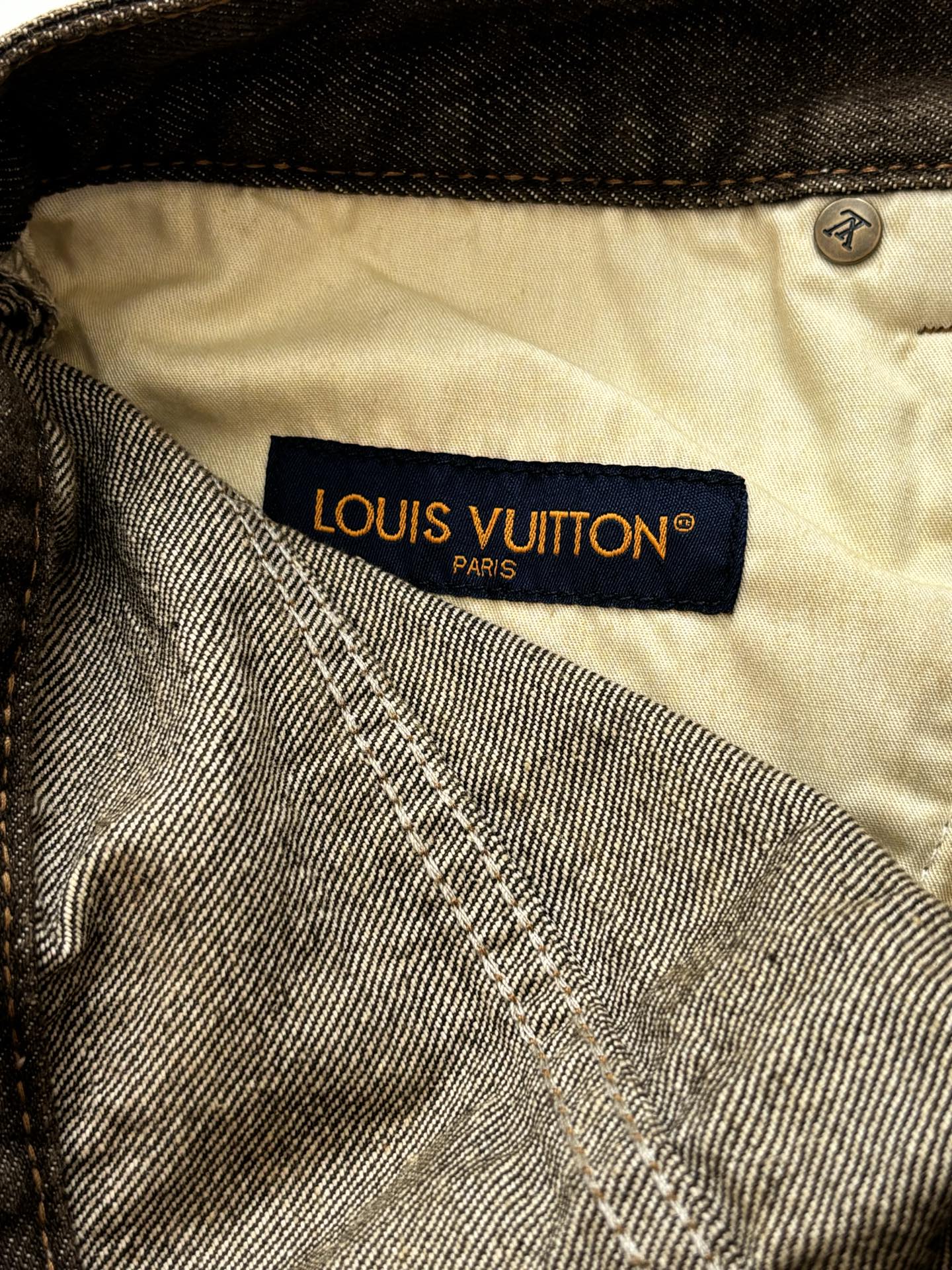 Beige waistband lining with LOUIS VUITTON Paris label on dark denim pants