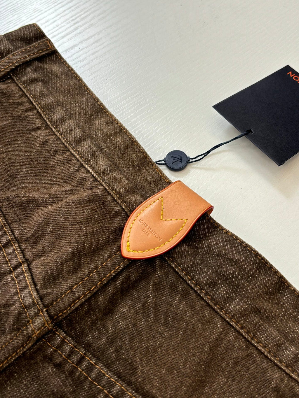 Louis Vuitton brown denim pants with tan leather logo patch and double-stitched seams
