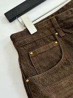 Brown denim pants pocket with gold-tone buttons and visible stitched seams.