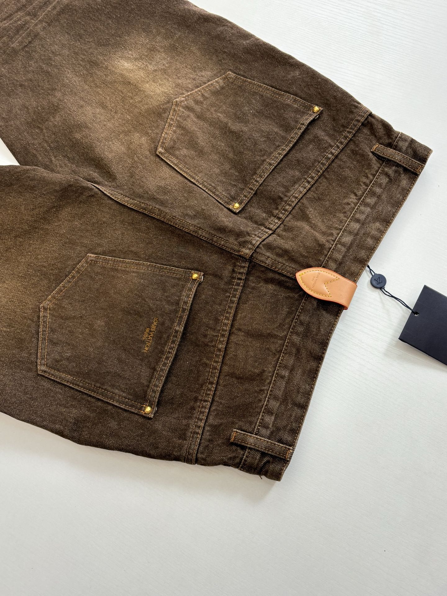 Brown denim pants with back patch pockets and straight stitched seam lines.