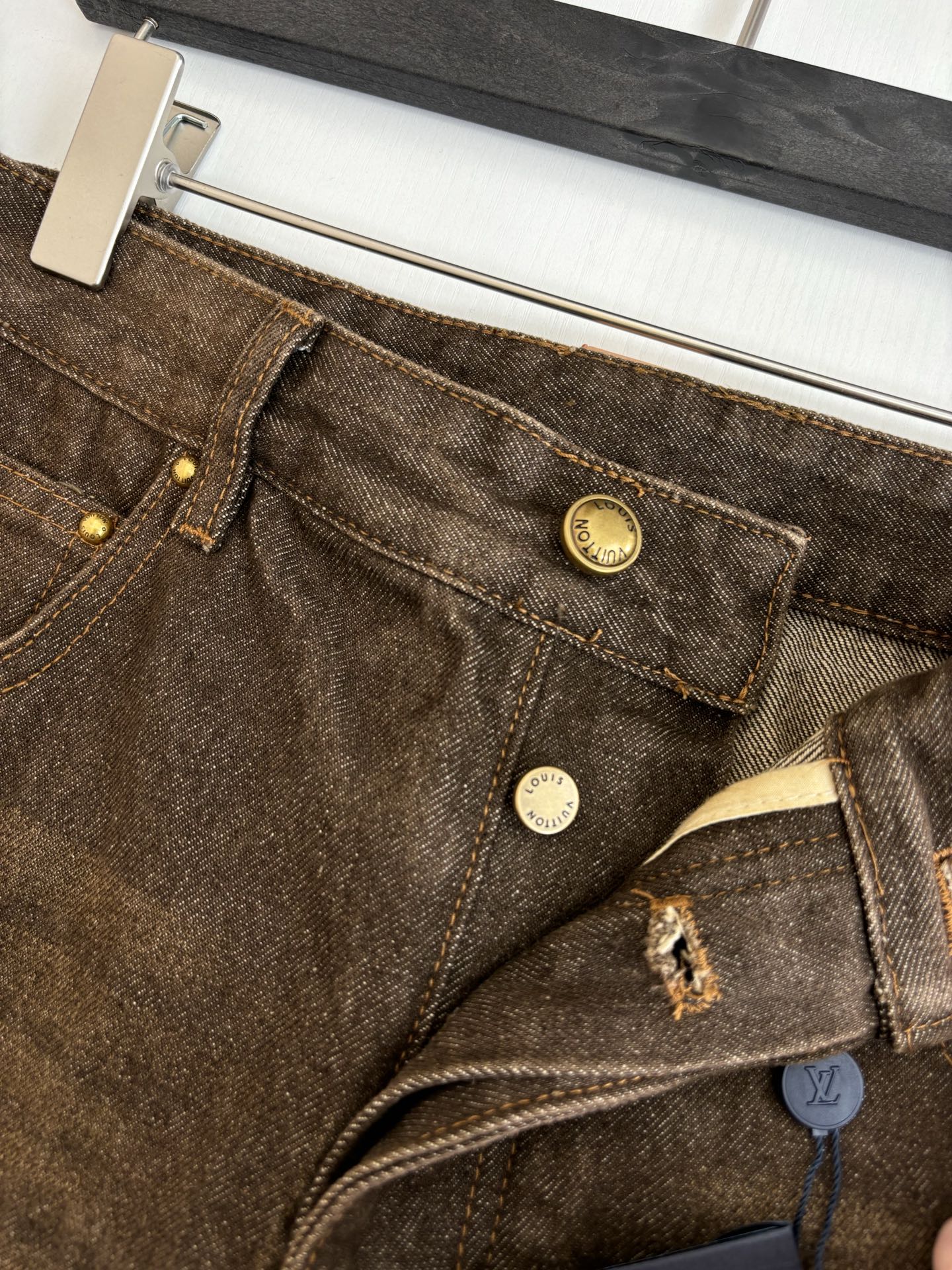 Brown denim pants waistband with coin detail, button closures, and belt loops.