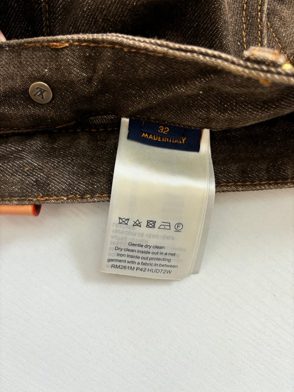 Denim pants with size 32 label, Made in Italy care tag, and button