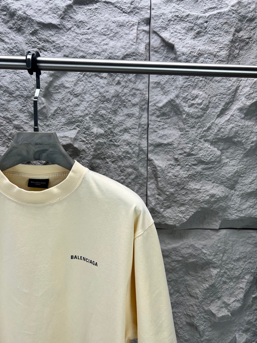 Cream short-sleeve T-shirt with BALENCIAGA logo at left chest, close-up view.