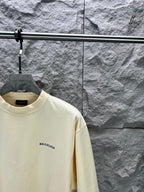 Cream short-sleeve T-shirt with BALENCIAGA logo at left chest, close-up view.