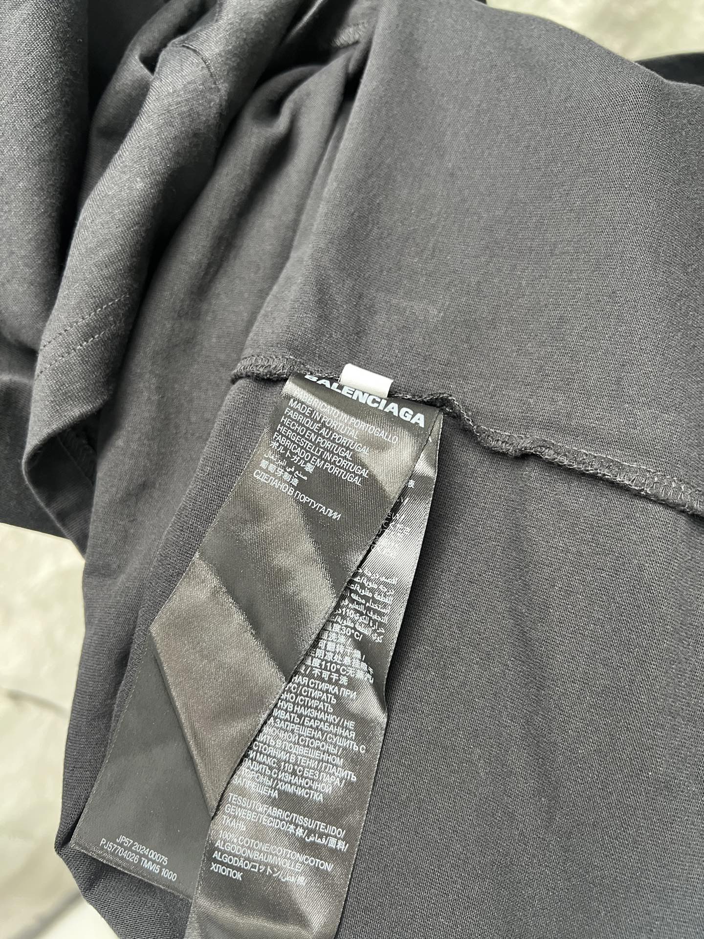 Balenciaga T-shirt care label stitched on gray fabric near seam