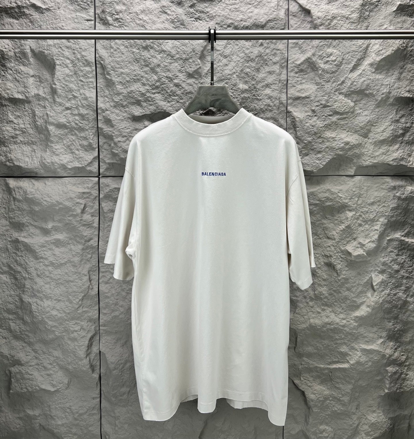 White crew-neck T-shirt on hanger with small Balenciaga logo on chest