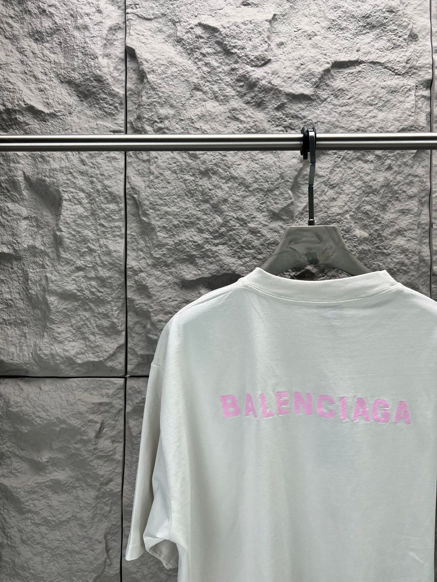 White T-shirt with large pink BALENCIAGA logo on back, close-up
