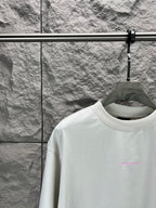 White T-shirt collar with small pink logo at left chest